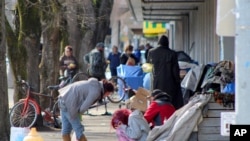 FILE - Homeless people crowd a sidewalk in downtown Salem, Oregon, March 3, 2020. A $20 billion funding effort by the Trump administration aims to support providers of mental health and substance abuse services during the coronavirus pandemic. 