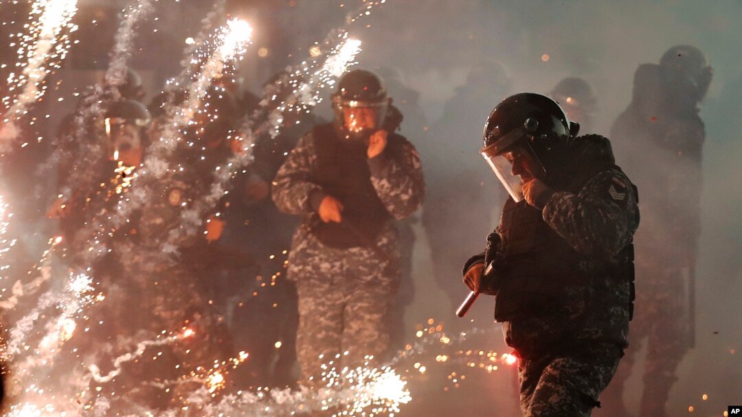 Lebanese riot police run from firecrackers thrown by supporters of the Shiite Hezbollah and Amal Movement groups, who were trying to attack anti-government protesters, in Beirut, Dec. 14, 2019. 