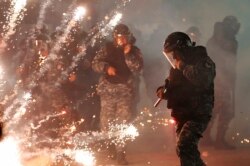 Lebanese riot policemen run from firecrackers that fired by the supporters of the Shiite Hezbollah and Amal Movement groups, as they try to attack the anti-government protesters squares, in downtown Beirut, Dec. 14, 2019.