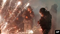 Lebanese riot police run from firecrackers thrown by supporters of the Shiite Hezbollah and Amal Movement groups, who were trying to attack anti-government protesters, in Beirut, Dec. 14, 2019. 