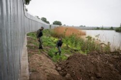 Police officers patrol alongside a steel wall at Evros river, near the village of Poros, at the Greek -Turkish border, Greece, May 21, 2021.