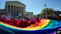 FILE - Demonstrators stand in front of a rainbow flag of the Supreme Court in Washington.