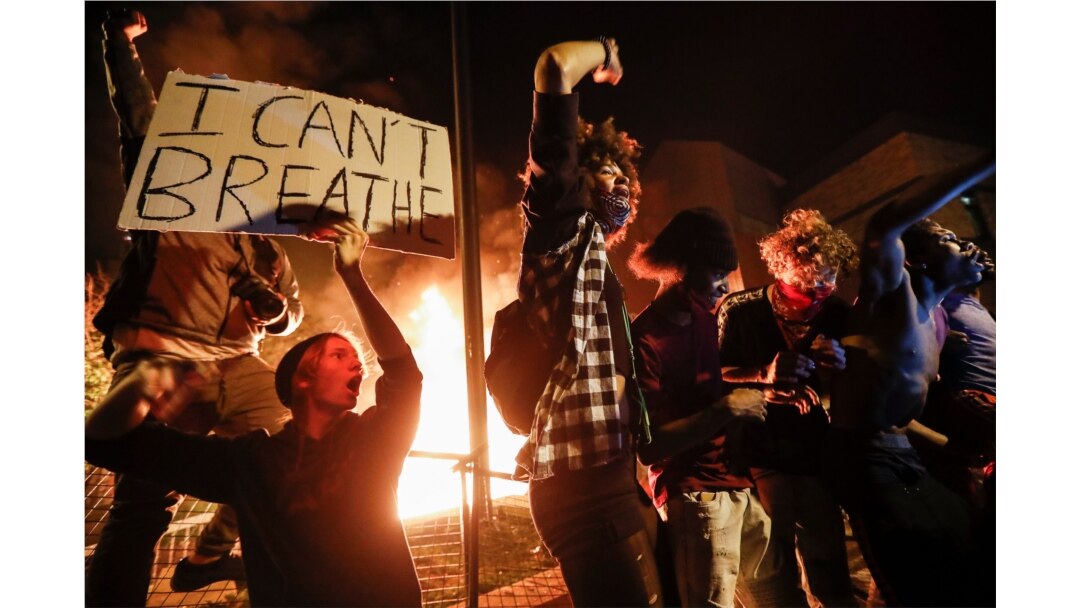Protesters demonstrate outside a burning Minneapolis 3rd Police Precinct, May 28, 2020, in Minneapolis.