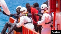 Seorang migran ditolong oleh petugas penyelamat saat tiba di Pelabuhan Arguineguin di Pulau Canary, Gran Canaria, Spanyol, 30 Mei 2016. Migran itu adalah bagian dari rombongan 58 migran yang dicegat sekitar 100 mil dari pantai. 