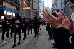 Protesters cheer front line protesters during their annual pro-democracy march on New Year's Day in Hong Kong, Jan. 1, 2020.