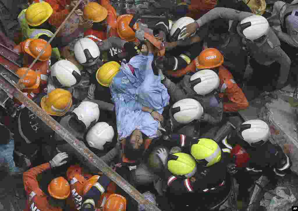 Rescuers carry out a survivor from the site of a building that collapsed in Mumbai, India. The four-story apartment building collapsed in a crowded neighborhood. Several people were feared to be trapped, an official said.