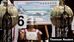 Una niña sostiene el número seis frente a un boleto de la lotería mexicana durante la realización del sorteo simbólico del lujoso avión presidencial, realizado en un edificio del gobieno en Ciudad de México, el 15 de septiembre de 2020.