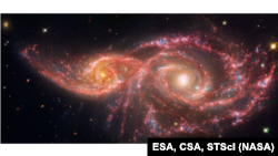 This image released by NASA’s James Webb Space Telescope, and NASA’s Hubble Space Telescope shows IC 2163, the small spiral galaxy on the left passing behind NGC 2207, the larger spiral galaxy at right. The galaxies grazed one another millions of years ago. Both galaxies have high star formation rates. Each year, the galaxies produce the equivalent of two dozen new stars that are the size of the Sun.