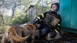 A firefighter pets a dog as he rests after putting out a fire in a private house hit by Russian shelling in Kharkiv, Ukraine, on May 3, 2024.