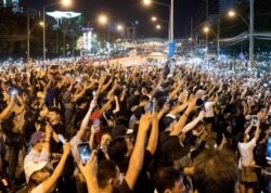 Protesters turn on mobile phones with lights during a rally outside the headquarters of the Siam Commercial Bank, a publicly-held company in which the Thai king is the biggest shareholder, in Bangkok, Thailand, Nov. 25, 2020.