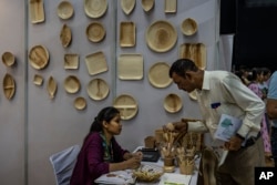 A visitor asks about eco-friendly products at an event to create awareness about eco-friendly products in New Delhi, India on July 1, 2022. (AP Photo/Altaf Qadri)