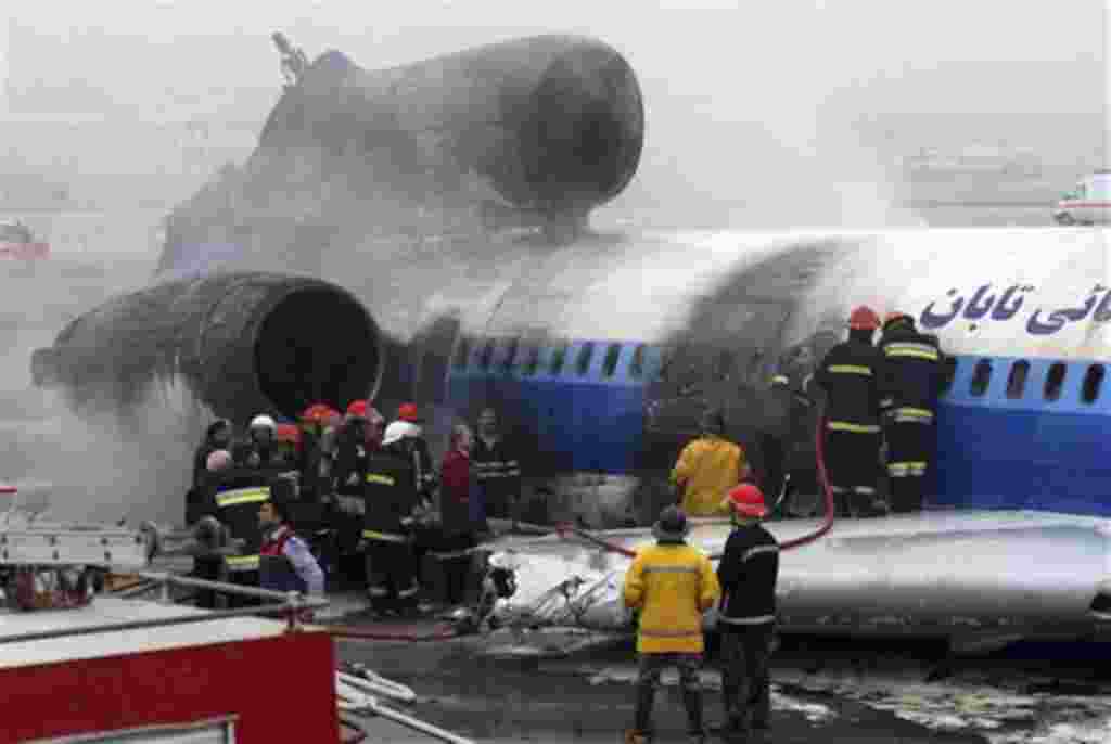 Iranian firefighters work on a burned Russian-made Iranian passenger plane after its crash landing at Mashhad airport, northeastern Iran, Sunday, Jan. 24, 2010. The Tupolev passenger plane carrying 157 passengers and 13 crew crash landed in northeastern I