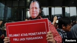 Seorang demonstran mengenakan topeng bergambar Ketua KPK Firli Bahuri dalam unjuk rasa di luar kantor Komisi Pemberantasan Korupsi di Jakarta, Jumat 23 November 2023. (Foto: Ajeng Dinar Ulfiana/Reuters)