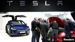 Visitors inspect Tesla electric cars at Brussels Motor Show, Belgium, Jan. 18, 2019. 