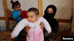 FILE - Syrian refugee Asheqa holds her unregistered baby daughter Nour inside a tent at a refugee camp near the town of Baalbek in Lebanon's Bekaa valley, March 3, 2016. (REUTERS/Mohamed Azakir)