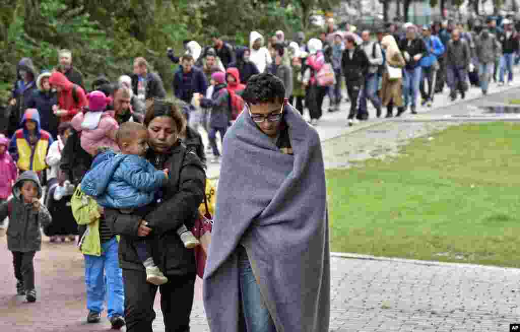 Para migran dari stasiun kereta api utama di Dortmund, Jerman, berjalan menuju gedung tempat mereka dikumpulkan (6/9).&nbsp;​(AP/Martin Meissner)