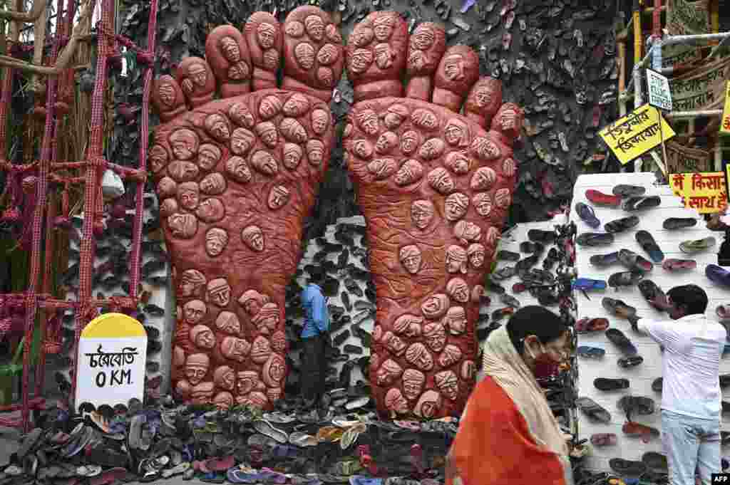 A person walks past workers decorating a makeshift place of worship for Durga Puja, with a theme in support of the ongoing farmers&#39; protest against the central government&#39;s agricultural reforms, in Kolkata, India.