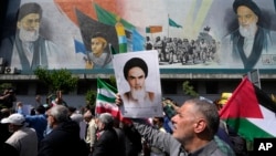 FILE—Iranian worshippers walk past a mural showing the late revolutionary founder Ayatollah Khomeini, right, Supreme Leader Ayatollah Ali Khamenei, left, and Basij paramilitary force, in an anti-Israeli gathering after Friday prayers in Tehran, Iran, April 19, 2024.