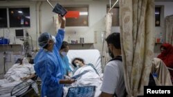 အိန္ဒိယနိုင်ငံ နယူးဒေလီမြို့က ဆေးရုံတခုမှာ ကိုဗစ်ကူးစက်လူနာတွေကို ကုသပေးနေတဲ့ ကျန်းမာရေးဝန်ထမ်းများ။ (မေ ၀၁၊ ၂၀၂၁)