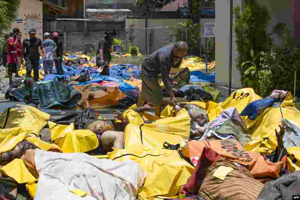 People attempt to identify the bodies of their relatives at the compounds of a police hospital in Palu, Indonesia&#39;s Central Sulawesi following a strong earthquake in the area. The death toll from a powerful earthquake and tsunami leapt to 832 as stunned people on the stricken island of Sulawesi struggled to find food and water and looting spread.