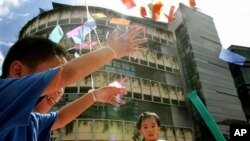 Anak-anak bermain di depan gedung Universitas Manajemen Singapura. (AP/Wong Maye-e)