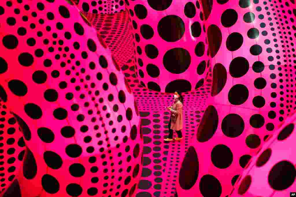 A woman walks through the art work &#39;A Bouquet of Love I Saw in the Universe&#39; by Yayoi Kusama during the press preview of a retrospective exhibition of the Japanese artist at the Martin Gropius Bau museum in Berlin, Germany.