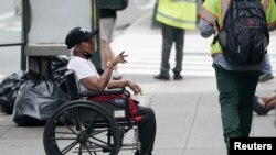 Un hombre en silla de ruedas pide dinero a transeúntes en Manhattan, Nueva York, 7 de agosto de 2020.