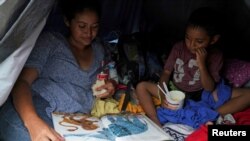 Madre solicitante de asilo de El Salvador le lee a su hijo de cuatro años en una tienda de campaña donde viven después de ser enviados de regreso bajo los Protocolos de Protección al Migrante (MPP) en Matamoros, México el 30 de octubre de 2019.
