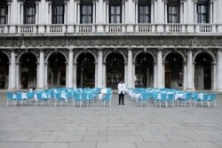A waiter stands by empty tables outside a restaurant at St Mark's Square, which is usually full of tourists, after Italy's government adopted a decree with new emergency measures to contain the coronavirus, in Venice, Italy, March 5, 2020.