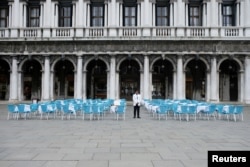 A waiter stands by empty tables outside a restaurant at St Mark's Square, which is usually full of tourists, after Italy's government adopted a decree with new emergency measures to contain the coronavirus, in Venice, Italy, March 5, 2020.