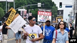 FILE - Strikers carry signs as writers and actors staged a solidarity march through Hollywood to Paramount Studios on Sept. 13, 2023 amid a halt in movie and TV production as the dual labor shortages continue.