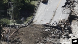 People gather alongside workers making repairs on Route 4 in Killington, Vermont, Aug. 30, 2011