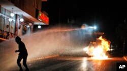 FILE - A demonstrator dodges spray from a Turkish police water canon during clashes between police and people protesting Turkey's operations against Kurdish militants in Istanbul, Aug. 16, 2015.