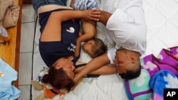 Honduran family Nolvia Luja, left, Willian Bonilla, and their son Wilmer Bonilla, who attended the annual Migrants Stations of the Cross caravan for migrants' rights, rest at a shelter in Tlaquepaque, Jalisco state, Mexico, April 18, 2018.