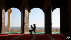 FILE - A Palestinian youth reads verses of the Quran, Islam's holy book, during the holy Islamic month of Ramadan at the beach side Mosque in Gaza City, June 9, 2016. 