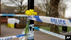 FILE - Daffodils are placed by a police cordon backdropped by a tent covering the area where former Russian double agent Sergei Skripal and his daughter were found critically ill following exposure to the Russian-developed nerve agent Novichok in Salisbury, England, March 13, 2018. 