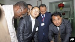 Chinese Embassy representatives sign handover papers to receive the body of a Chinese worker killed during a kidnapping, from a Sudanese Red Crescent representative (L) and a Sudanese Foreign Ministry official at the Chinese-run Hawasha hospital, in Khart