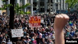 A protester raises a fist as thousands gather outside City Hall against the death in Minneapolis police custody of George Floyd, in front of City Hall in Seattle, June 1, 2020.