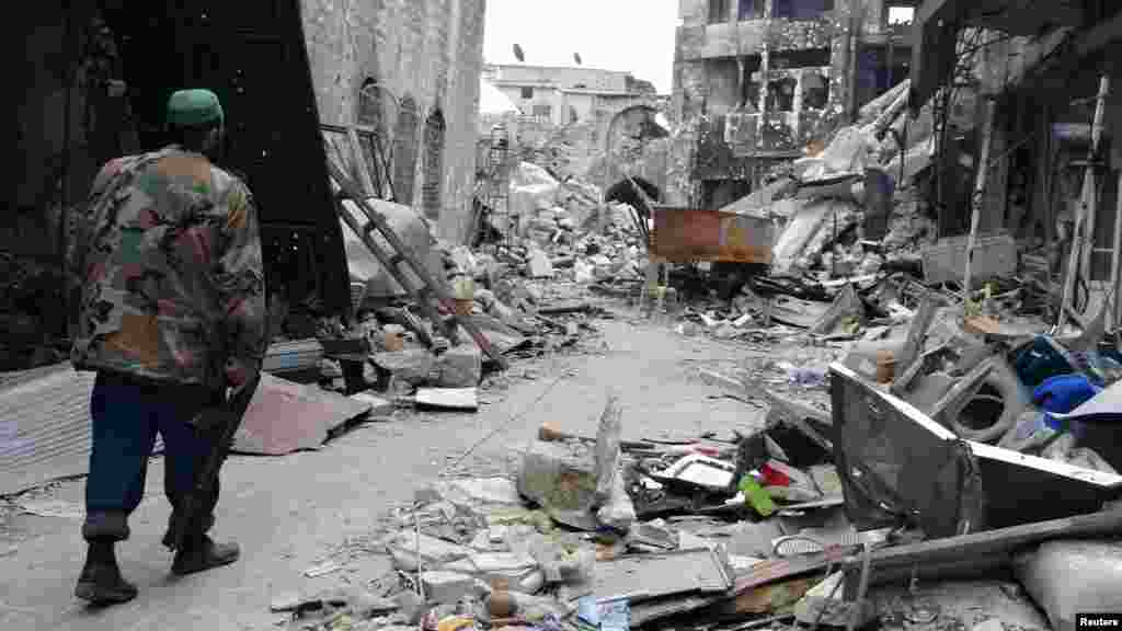 A Free Syrian Army fighter carries his weapon as he walks along a damaged street in Aleppo's Khan al-Wazeer district, Syria, December 16, 2012. 