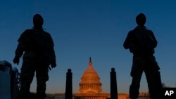 FILE - National Guard members stand their posts around the Capitol at sunrise in Washington, March 8, 2021. 