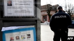 Policajac ispred table na kojoj stoje čitulje na Cetinju (Foto: SAVO PRELEVIC/AFP)