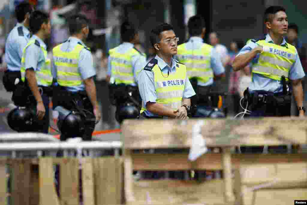 Policemen take their positions behind a barricade set up by pro-democracy demonstrators in the area they are occupying in the Mongkok shopping district, Hong Kong, Oct. 28, 2014. 