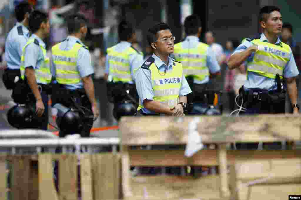 Policemen take their positions behind a barricade set up by pro-democracy demonstrators in the area they are occupying in the Mongkok shopping district, Hong Kong, Oct. 28, 2014.