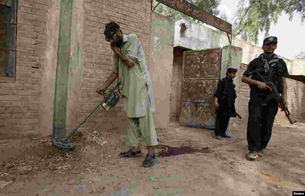 A security official uses a metal detector to survey the site of a bomb blast in the outskirts of Peshawar, Pakistan, Oct. 7, 2013. 