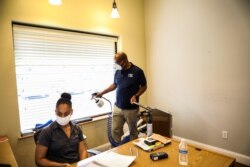 Yvon Brunache, owner of Marcel Interiors, sprays surface sanitizer inside of Marcel Interiors office space to prevent the spread of coronavirus disease (COVID-19) in Apopka, Florida, U.S., July 3, 2020.