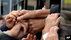 FILE - South Koreans and their North Korean relatives on a bus grip their hands each other to bid farewell after the Separated Family Reunion Meeting at Diamond Mountain resort in North Korea, Oct. 22, 2015.