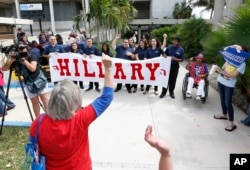Supporters of Democratic presidential candidate Hillary Clinton cheer for a television camera as they wait for a rally to begin where Clinton and former vice president Al Gore will speak, Oct. 11, 2016, in Miami.