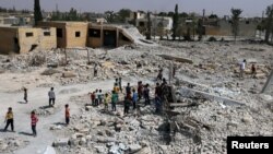 FILE - Pupils walk on debris of a damaged school in al-Saflaniyeh in eastern Aleppo's countryside, Syria, Sept. 17, 2017. 