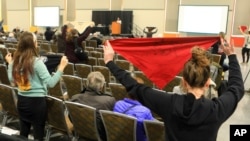 In this Feb. 11, 2019 file photo, protesters hold up flags during a public hearing on a draft environmental plan on proposed petroleum leasing within Alaska's Arctic National Wildlife Refuge in Anchorage, Alaska. 