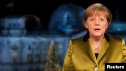 FILE - German Chancellor Angela Merkel poses for photographs after the recording of her annual New Year's speech at the Chancellery in Berlin, Dec. 30, 2013. 